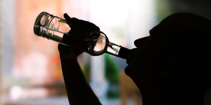 Silhouette of man drinking alcohol, close up